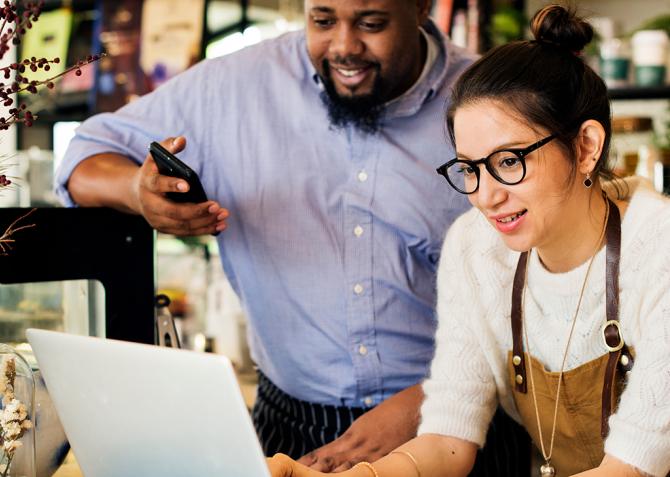 Two small business owners look at a laptop together in a shop.