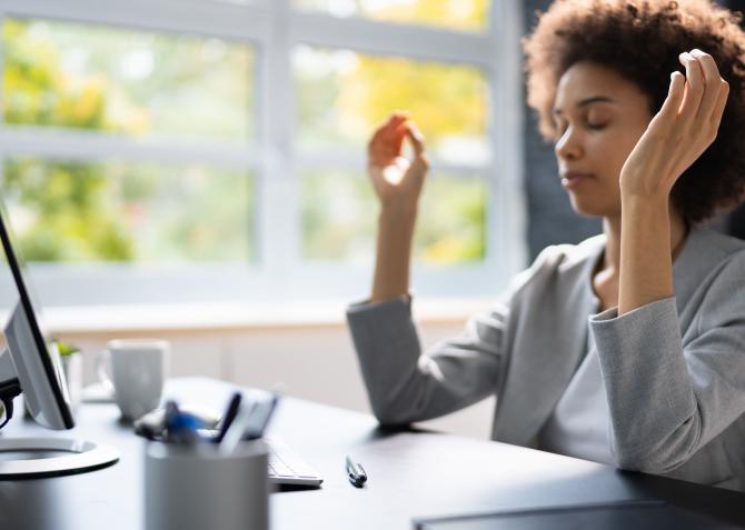 A business professional meditating at a desk.