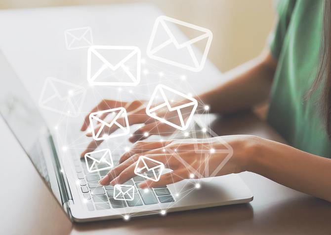 Email icons over a person typing on a laptop.