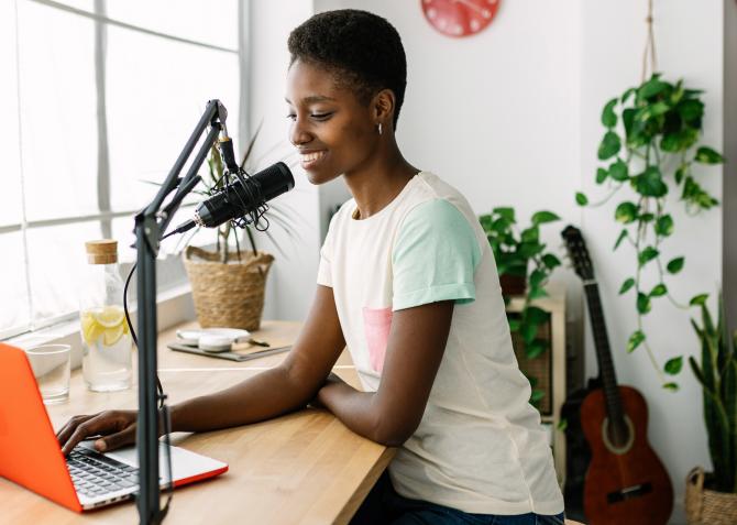 woman recording podcast on laptop with mic