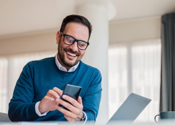 man smiling dialing into conference call on phone 
