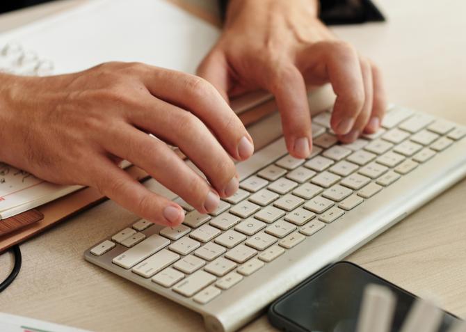man's hands typing on keyboard