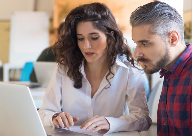 Two coworkers review sales leads on a laptop
