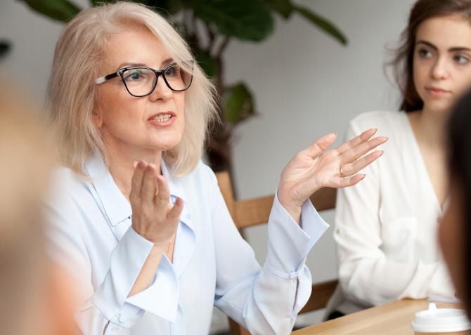 Mature businesswoman speaks to a group of mentees