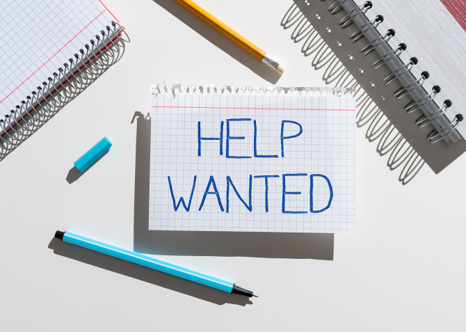 A piece of notebook paper with "Help Wanted" written on it. 