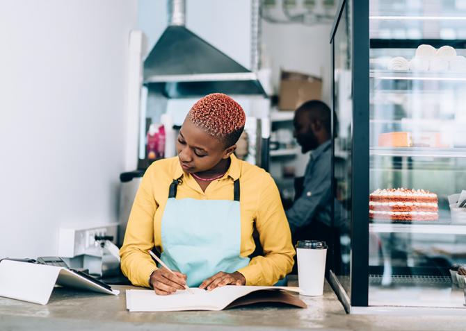 A small business owner tracks expenses while looking at a tablet device.