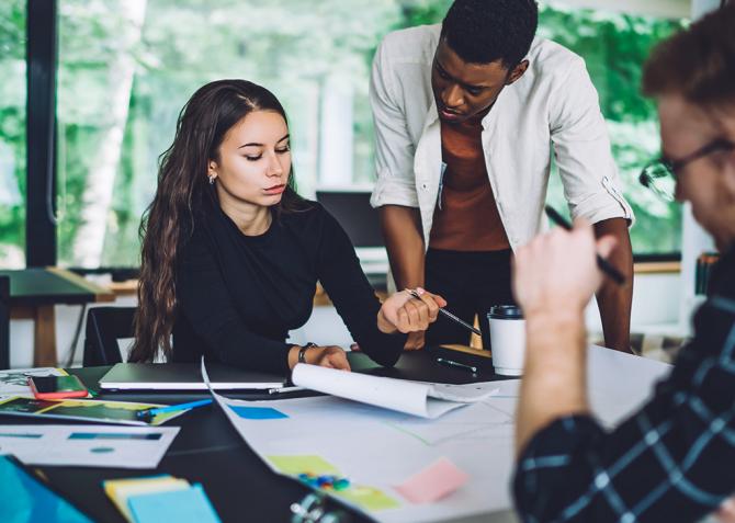 A group of business professionals discuss strategy around a table.