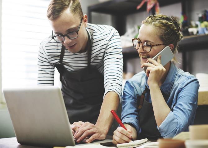 Two small business partners look at a laptop together.