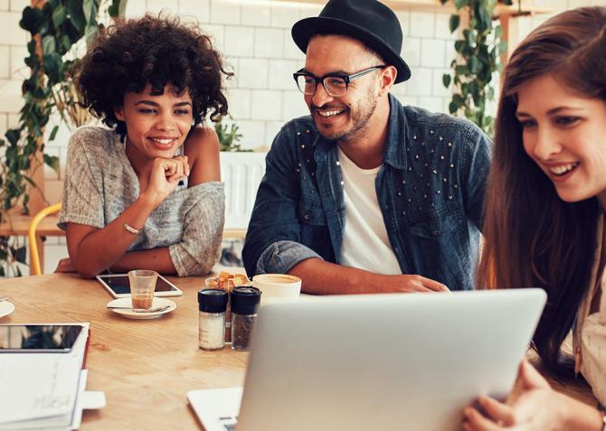 A group of business professionals looking at a laptop screen while sitting around a table.