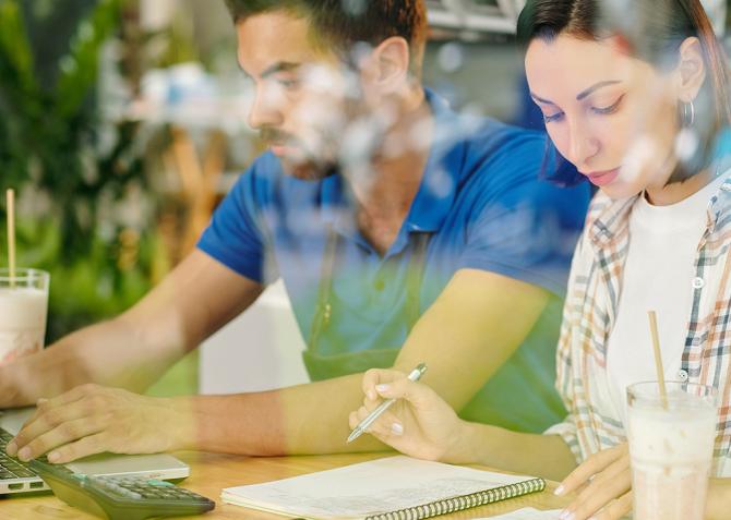 Two small business owners go over financing while sitting at a table.